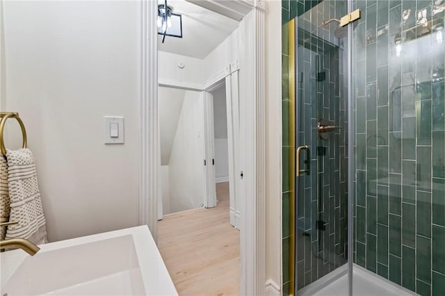 bathroom with wood-type flooring, a shower with shower door, and sink