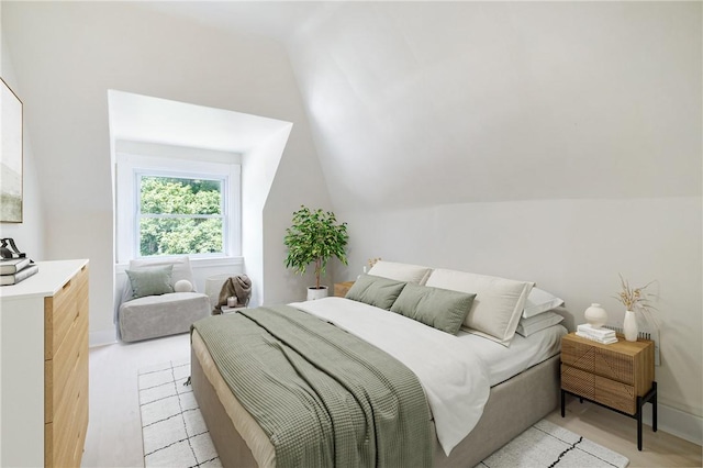 bedroom with vaulted ceiling and light wood-type flooring