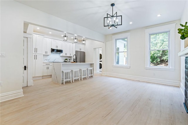 kitchen with appliances with stainless steel finishes, a kitchen breakfast bar, pendant lighting, a center island with sink, and white cabinets