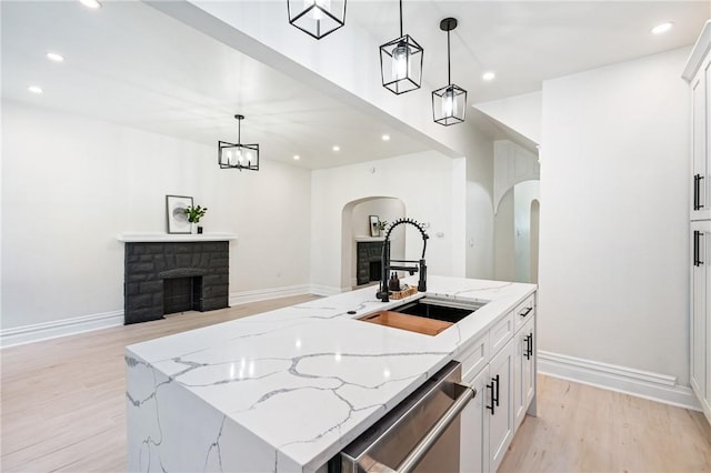 kitchen featuring a fireplace, pendant lighting, dishwasher, and an island with sink