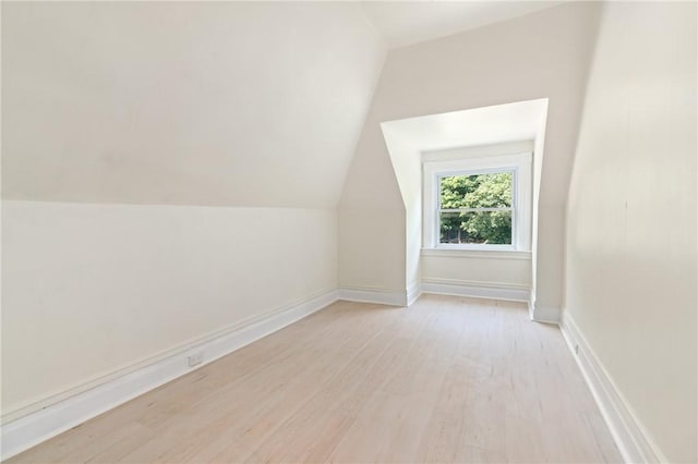 additional living space with light wood-type flooring and vaulted ceiling