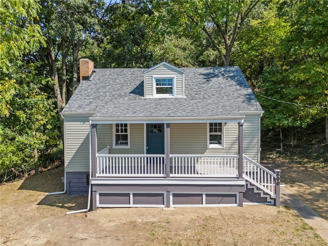 cape cod house with a front lawn and covered porch