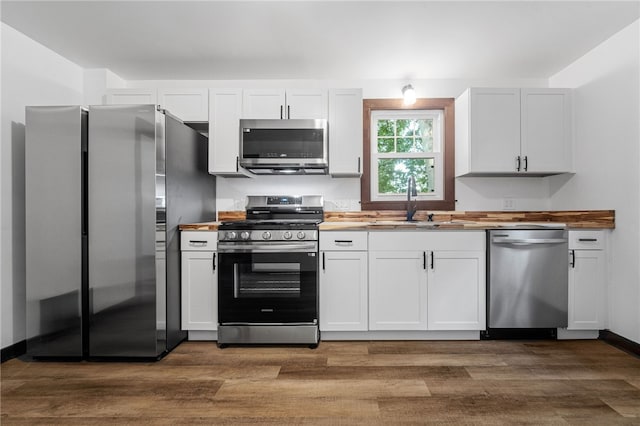 kitchen with wooden counters, appliances with stainless steel finishes, sink, dark hardwood / wood-style floors, and white cabinetry