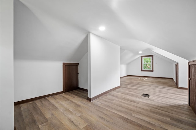 additional living space with vaulted ceiling and light hardwood / wood-style flooring