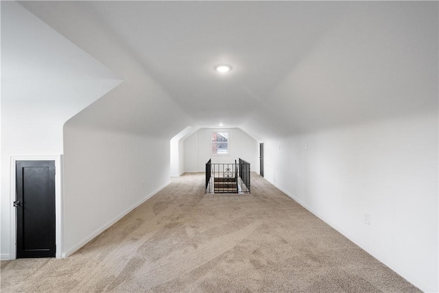 additional living space featuring light colored carpet and vaulted ceiling