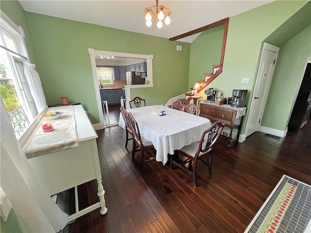 dining room featuring an inviting chandelier, a wealth of natural light, dark wood-type flooring, and sink