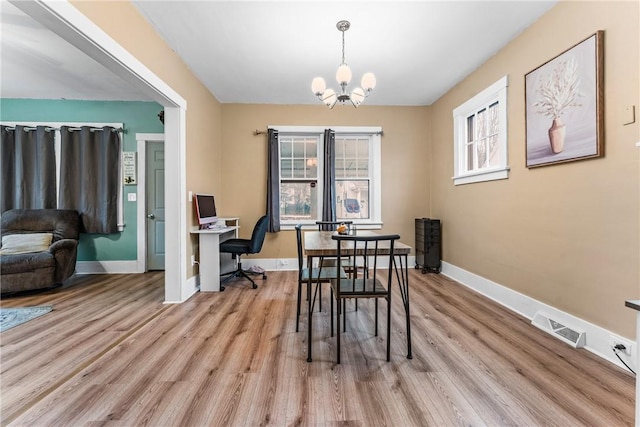 dining space featuring plenty of natural light, light wood-type flooring, and an inviting chandelier