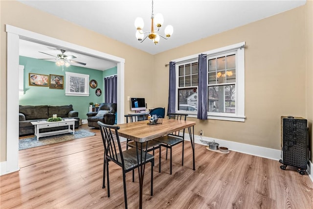 dining room with ceiling fan with notable chandelier and light hardwood / wood-style floors