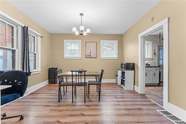 dining room with light hardwood / wood-style floors and a notable chandelier