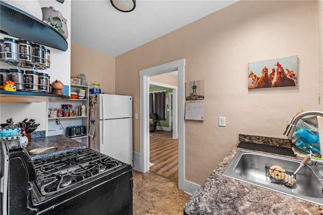 kitchen featuring black gas stove, white fridge, and sink