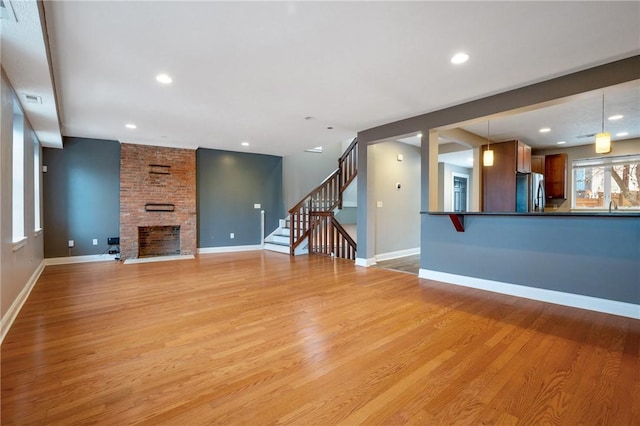 unfurnished living room featuring a large fireplace, light hardwood / wood-style flooring, and sink