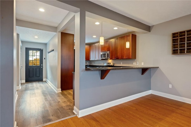 kitchen with a breakfast bar, light hardwood / wood-style floors, kitchen peninsula, and decorative light fixtures