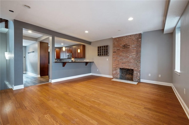 unfurnished living room with light wood-type flooring and a brick fireplace