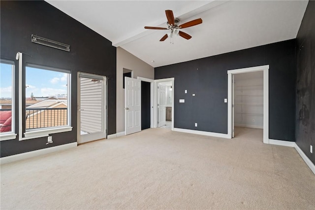 unfurnished bedroom featuring ceiling fan, lofted ceiling with beams, light colored carpet, a walk in closet, and a closet