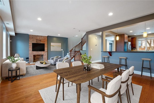 dining space featuring a fireplace, light wood-type flooring, and sink