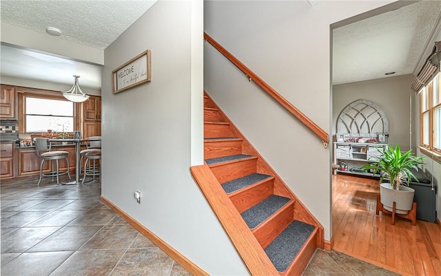 stairs with tile patterned flooring and a textured ceiling