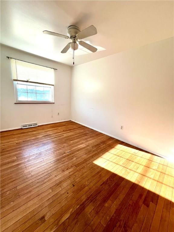 empty room with hardwood / wood-style flooring and ceiling fan