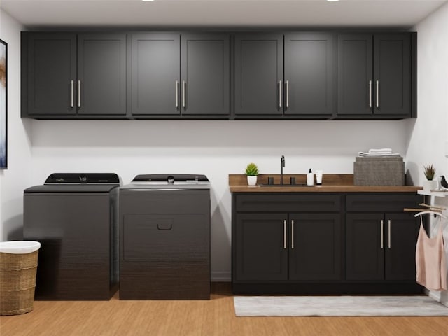 laundry area featuring cabinets, light hardwood / wood-style flooring, washing machine and clothes dryer, and sink