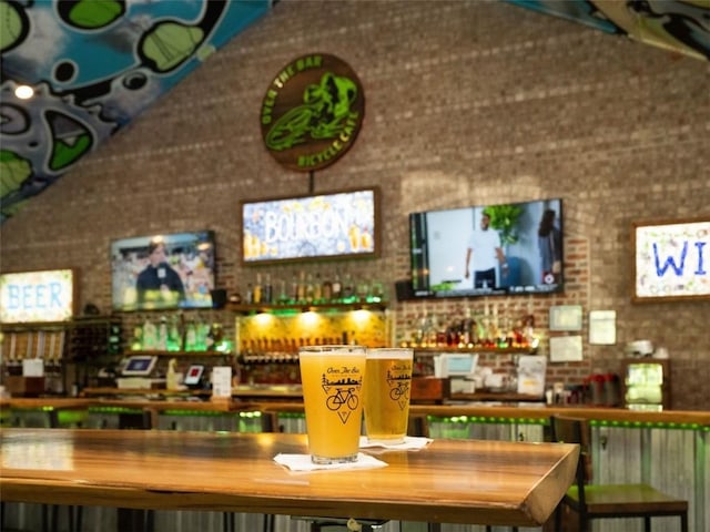 bar with lofted ceiling and brick wall