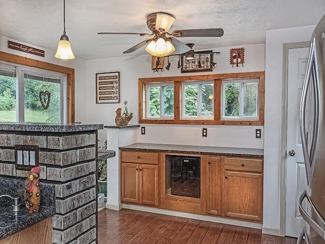 bar featuring stainless steel refrigerator, wine cooler, dark hardwood / wood-style floors, pendant lighting, and a textured ceiling