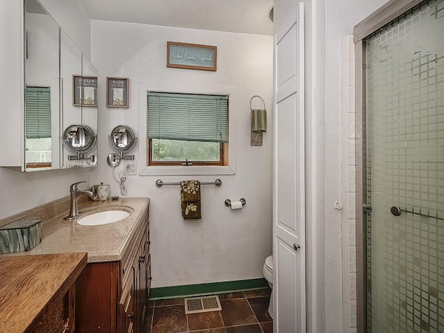 bathroom with vanity, toilet, and a shower with door