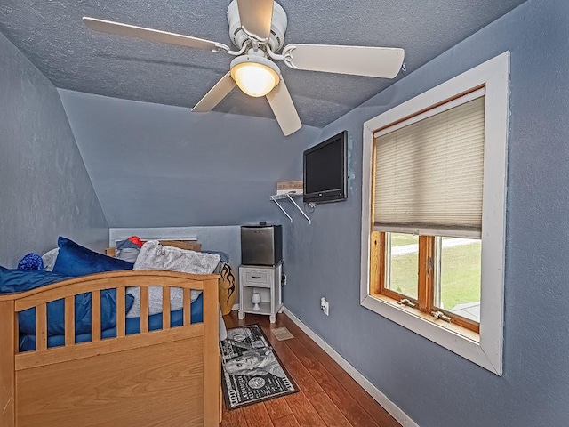 unfurnished bedroom featuring a textured ceiling, hardwood / wood-style flooring, ceiling fan, and lofted ceiling