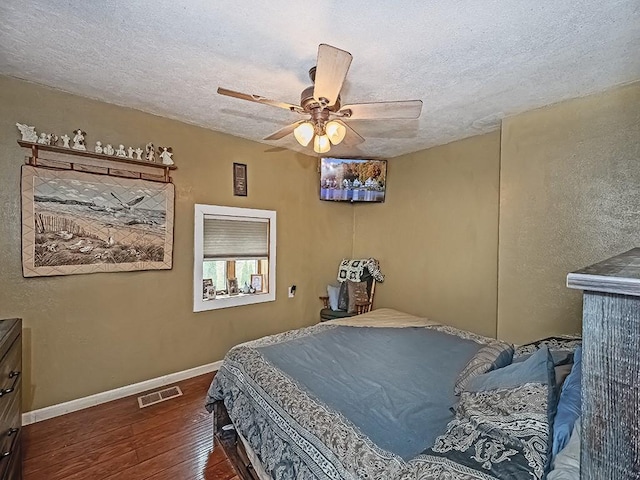 bedroom with a textured ceiling, ceiling fan, and dark hardwood / wood-style floors