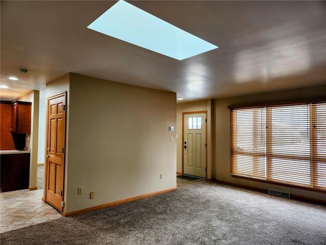 unfurnished living room featuring a skylight and light colored carpet