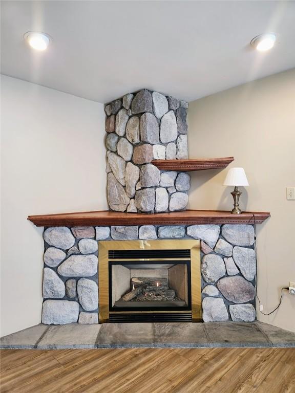 details with a stone fireplace and wood-type flooring