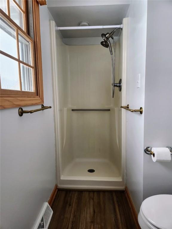 bathroom featuring hardwood / wood-style floors, toilet, and walk in shower