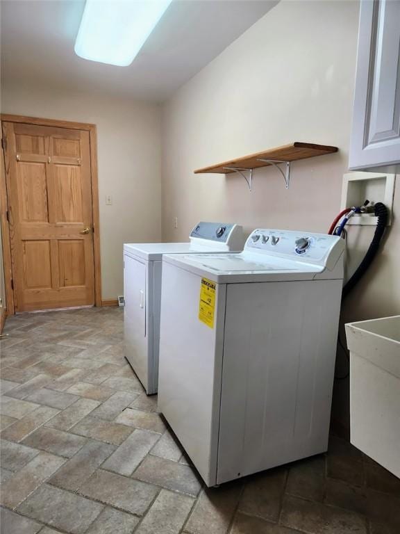 washroom with cabinets, independent washer and dryer, and sink