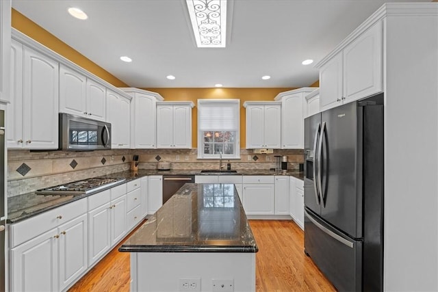 kitchen with white cabinetry, sink, a center island, light hardwood / wood-style flooring, and appliances with stainless steel finishes