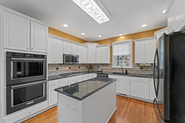 kitchen with appliances with stainless steel finishes, white cabinetry, and sink