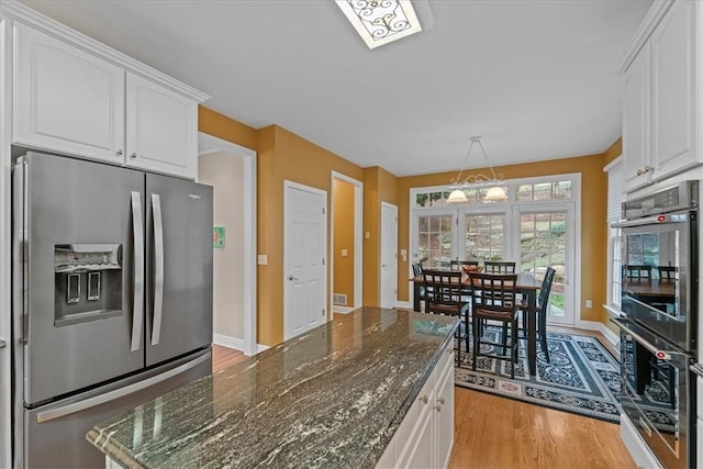 kitchen featuring dark stone countertops, stainless steel fridge with ice dispenser, white cabinets, and a chandelier