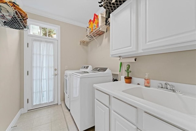 laundry area featuring washing machine and clothes dryer, sink, cabinets, crown molding, and light tile patterned floors