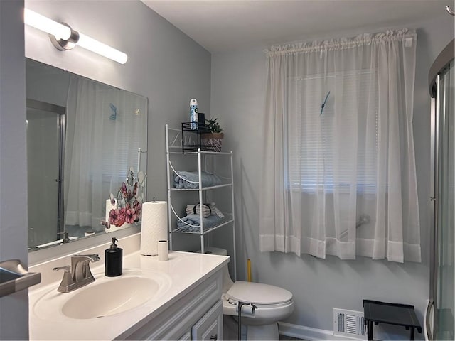 bathroom with vanity, toilet, and a shower with door