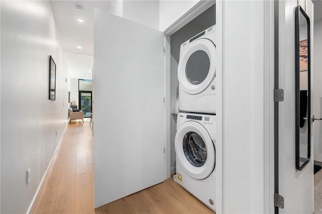 clothes washing area featuring light hardwood / wood-style flooring and stacked washing maching and dryer