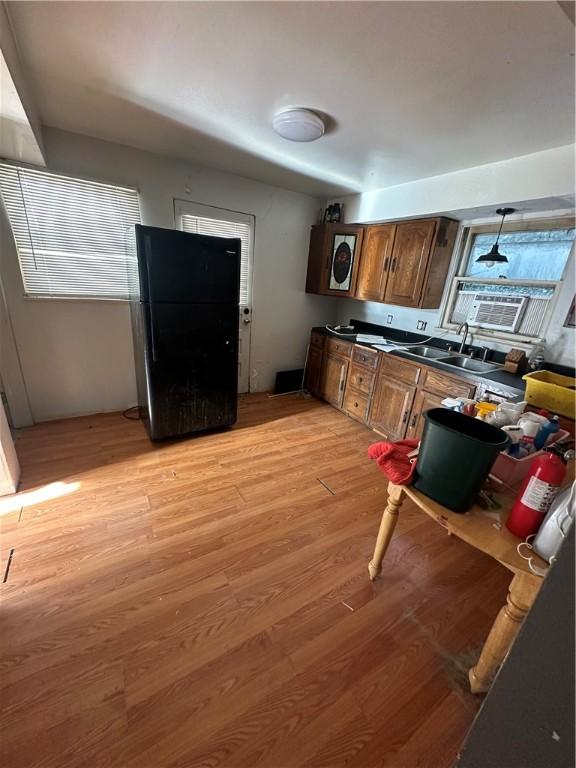 kitchen with black fridge, cooling unit, sink, pendant lighting, and light hardwood / wood-style flooring