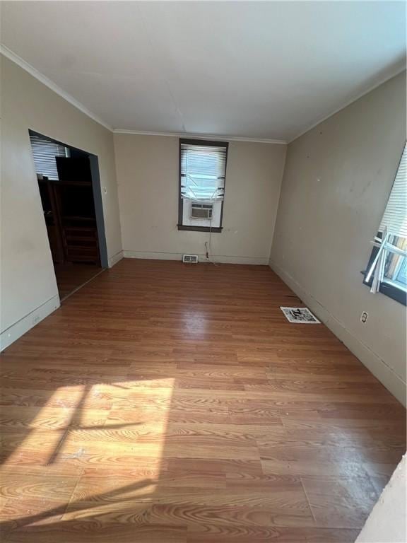 empty room with light hardwood / wood-style floors, cooling unit, and ornamental molding