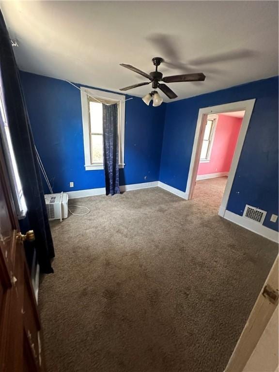 unfurnished room with carpet floors, a wall unit AC, and ceiling fan