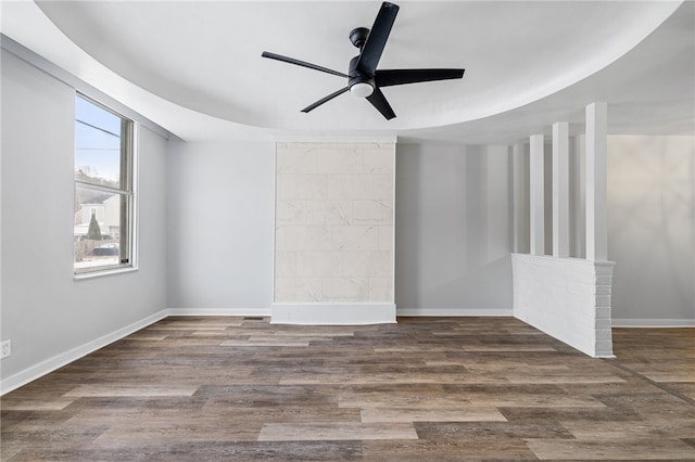 empty room with dark hardwood / wood-style floors, ceiling fan, and a raised ceiling