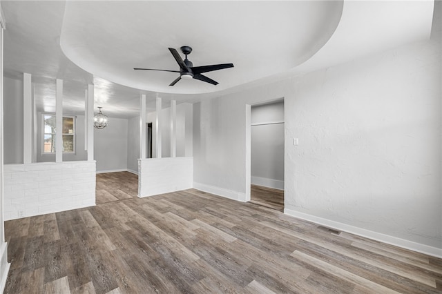 empty room with ceiling fan with notable chandelier and hardwood / wood-style flooring