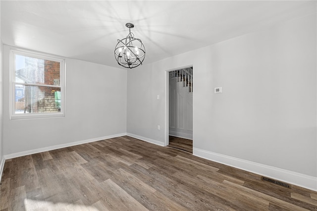 empty room featuring hardwood / wood-style flooring and an inviting chandelier