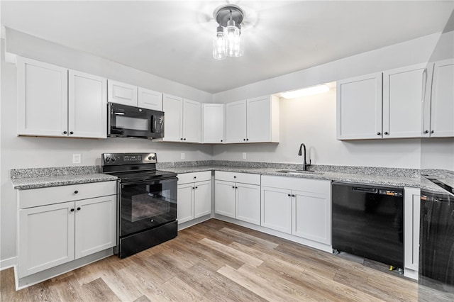 kitchen featuring white cabinetry, sink, light stone counters, light hardwood / wood-style floors, and black appliances