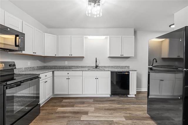 kitchen featuring light stone countertops, white cabinetry, sink, dark hardwood / wood-style flooring, and black appliances