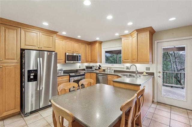 kitchen with light tile patterned flooring, appliances with stainless steel finishes, light brown cabinetry, and sink