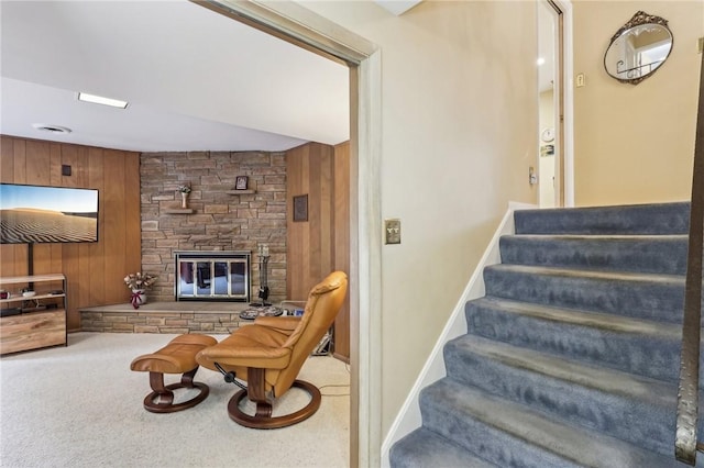 stairs with wood walls, a fireplace, and carpet