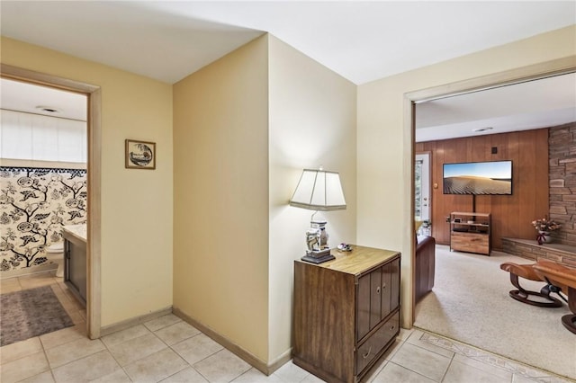 hall featuring wood walls and light tile patterned floors