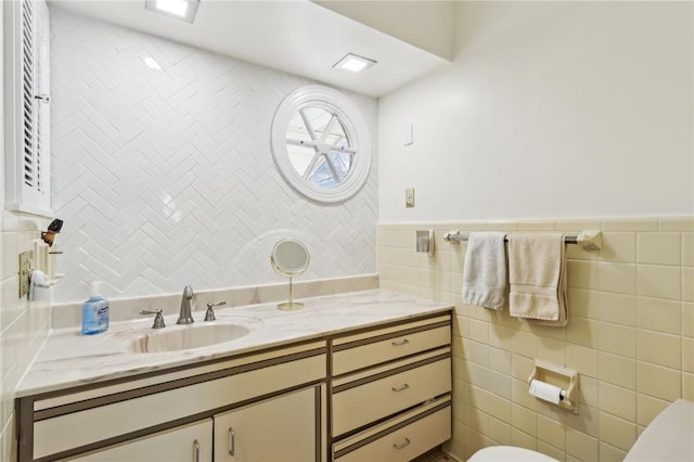 bathroom featuring vanity, toilet, and tile walls