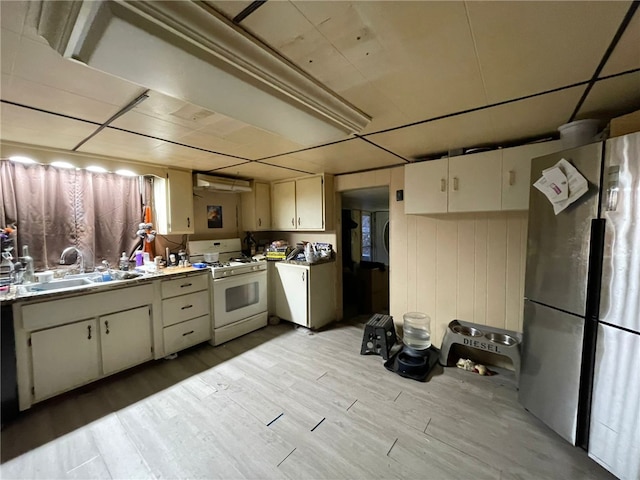 kitchen featuring sink, stainless steel fridge, cream cabinets, light hardwood / wood-style floors, and white gas range oven